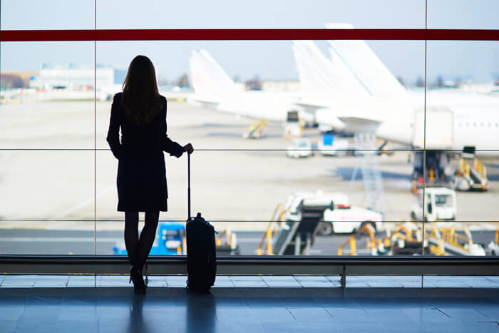 Kobieta z torbą na kółkach czeka na lotnisku w Norymberdze