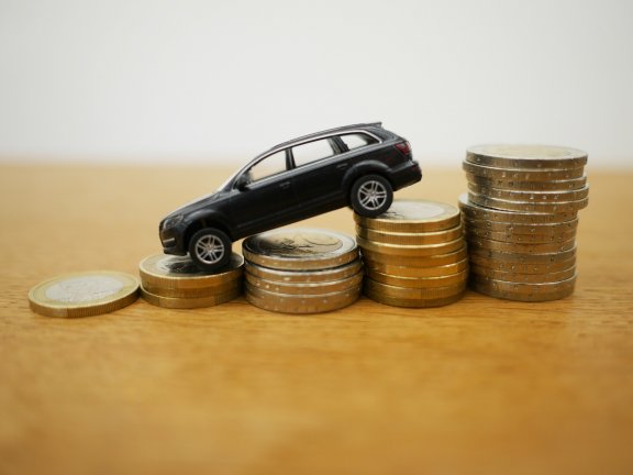 Toy car on euro coins – buying a car thanks to small VAT?