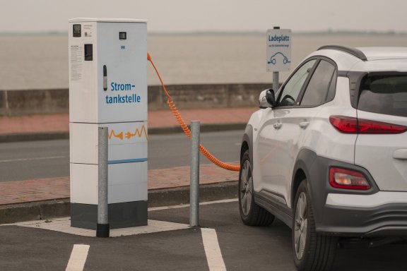 Electric car with charging cable plugged in at charging station
