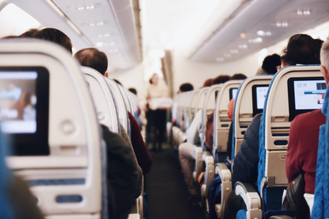 Passagiere im Flugzeug - Was ist bei Reisen während Corona zu beachten?