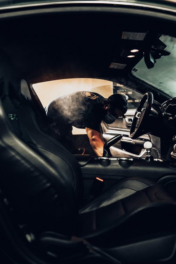 View through passenger door of a man cleaning the inside of the car