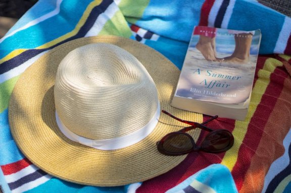 With a sun hat and book on the beach