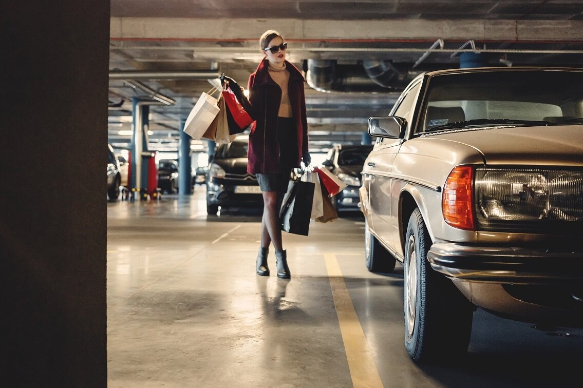 Eine Frau geht mit Einkaufstaschen zu Ihrem Auto im Parkhaus
