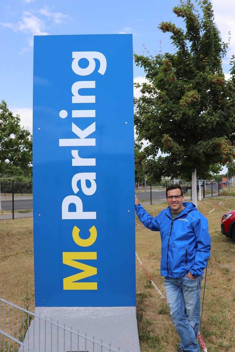 Operativer Leiter von McParking, Tino Schlockow, neben dem großen McParking-Logo