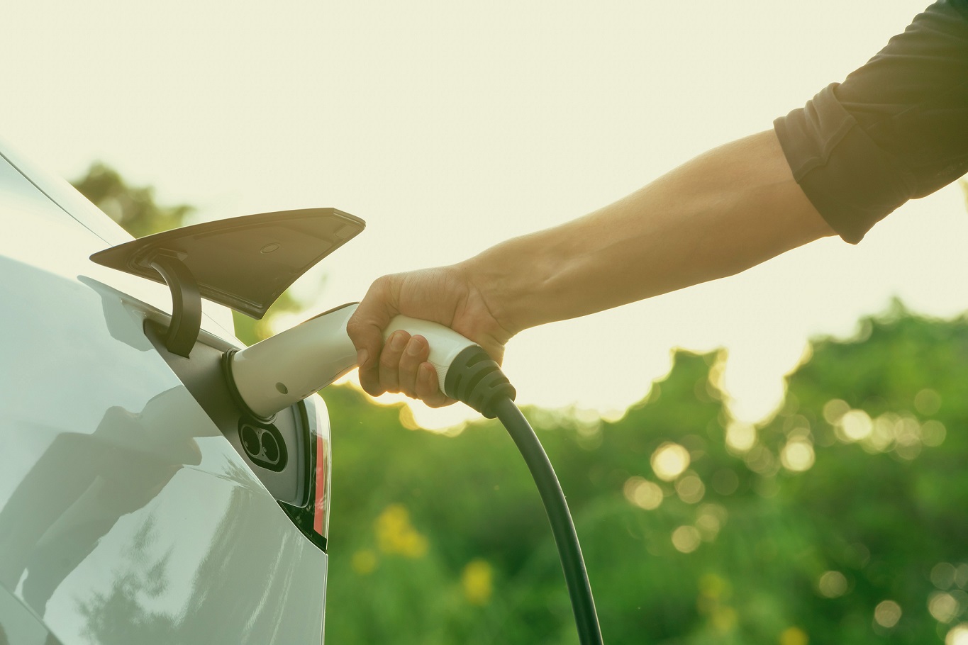 A man plugs the charging plug into his electric vehicle