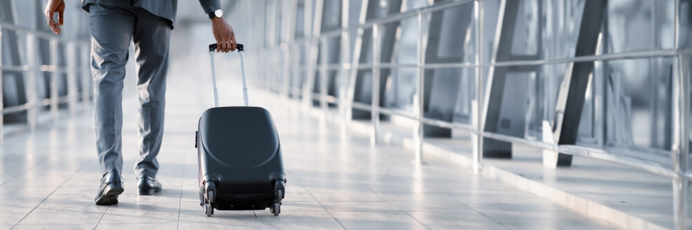 A man drags a suitcase behind him at the airport.