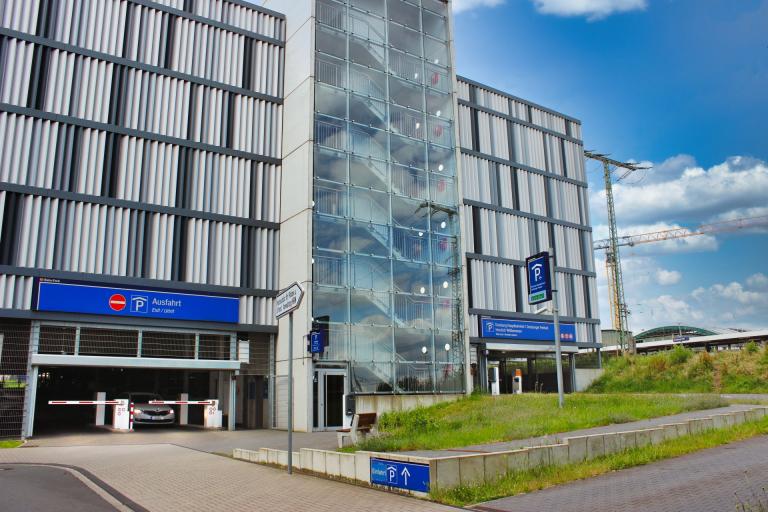 Image of the car park at Duisburg Central Station belonging to Contipark International Parking GmbH and DB Bahnpark. On the left side you can see the exit, on the right side the entrance. In the background you can see a blue sky with scattered