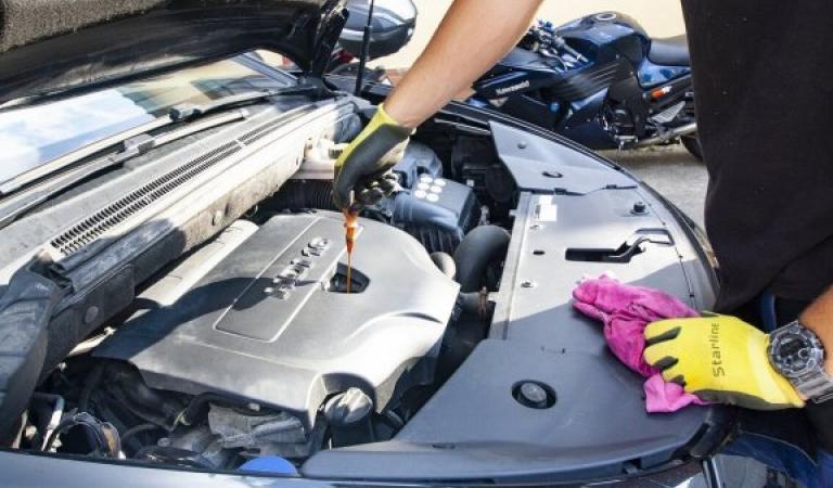 Car mechanic checks the oil level on the engine