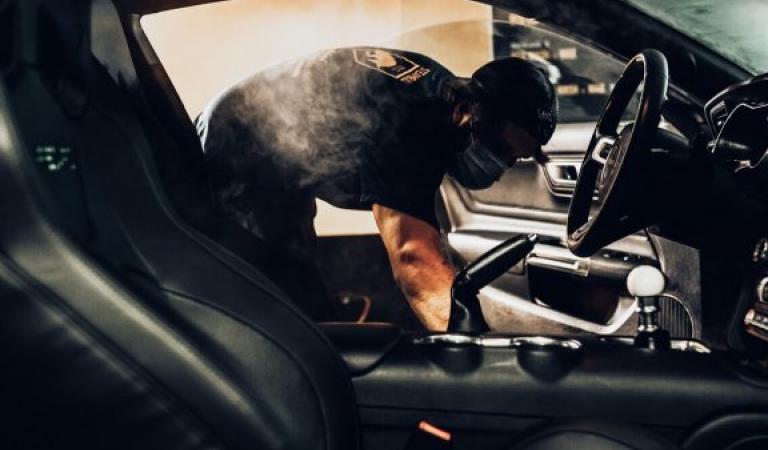 View through the passenger door of a man cleaning the inside of the car