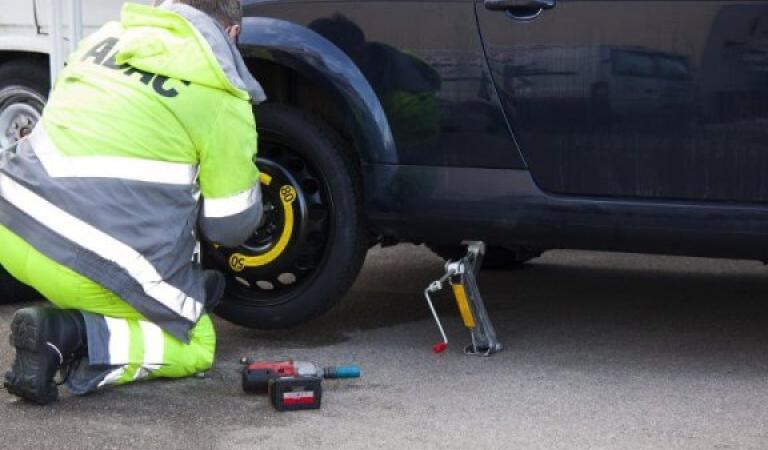 Muž mění pneumatiky na autě