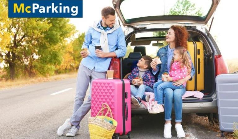 Rodina sedící u auta s kufry a nápoji